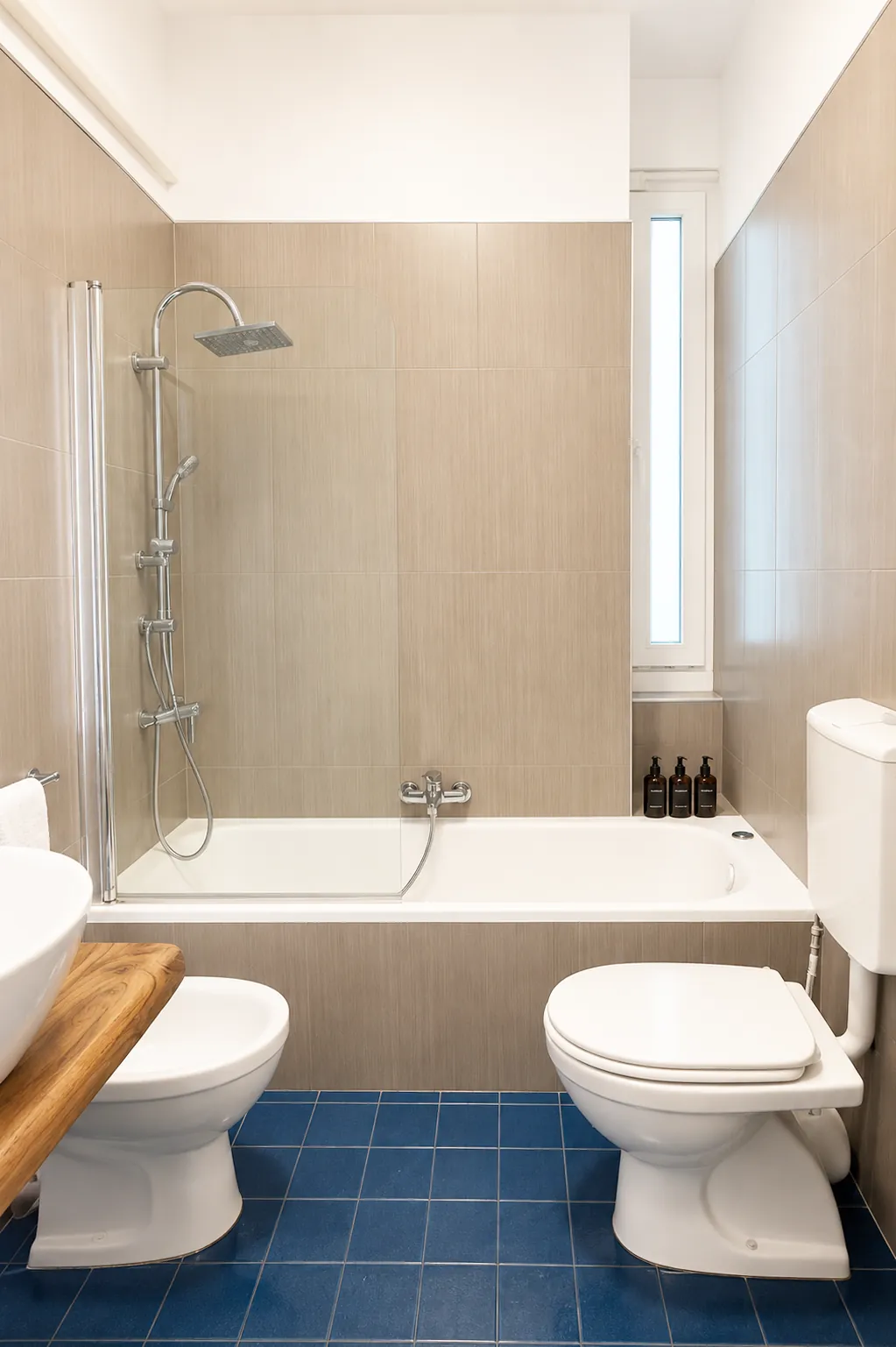 Bagno con vasca e doccia, piastrelle beige e pavimento blu