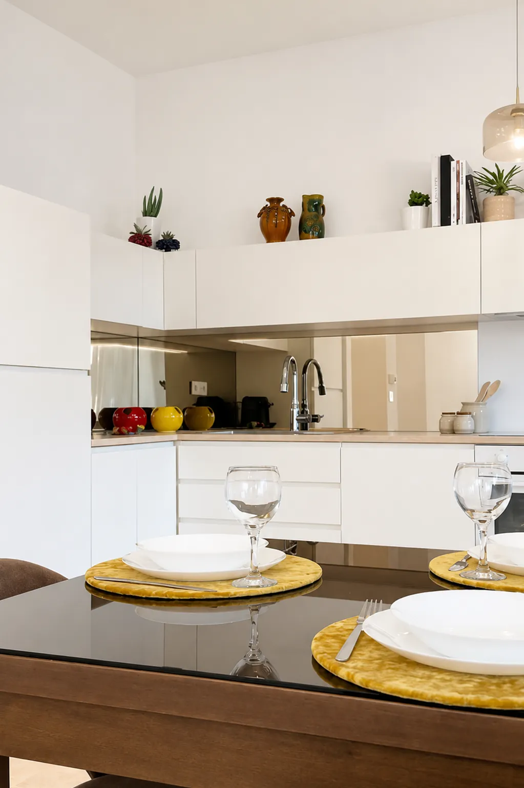 Cucina bianca con piatti e bicchieri sul tavolo e ceramiche sulle mensole